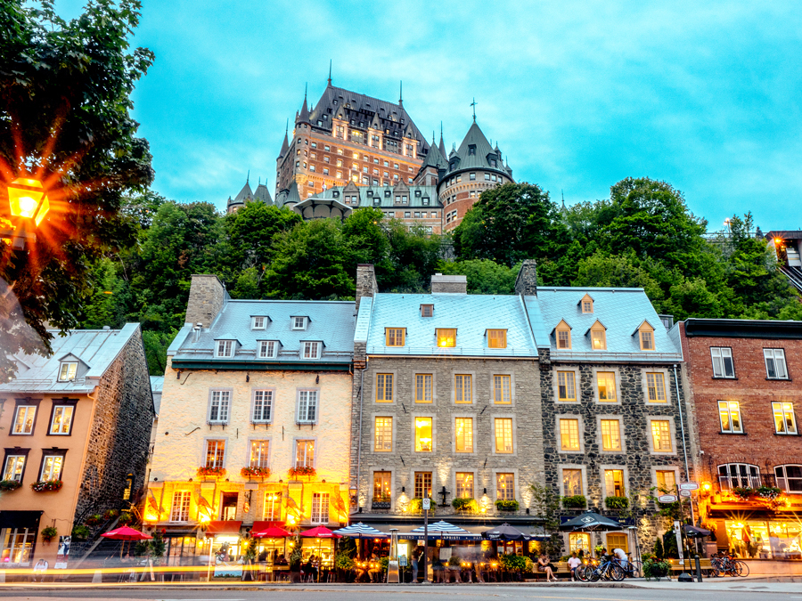 Historic stone buildings in Quebec City, Canada, with Château Frontenac looming on hilltop overhead