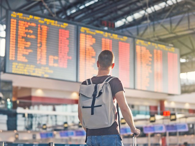 Traveler with backpack looking at airport departures and arrivals board