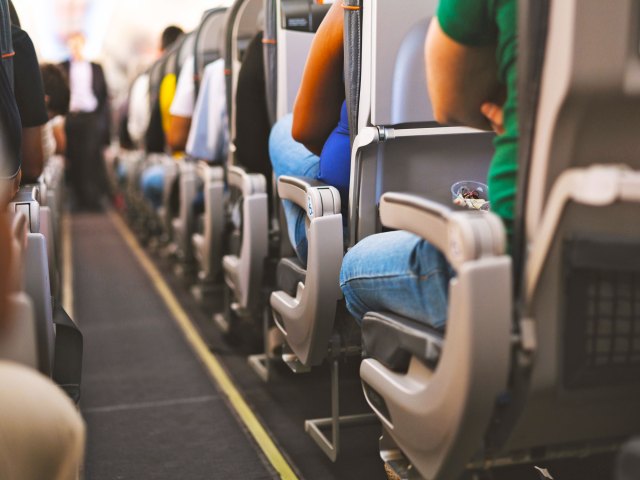 View of aircraft aisle looking toward front, with passengers seated on either side