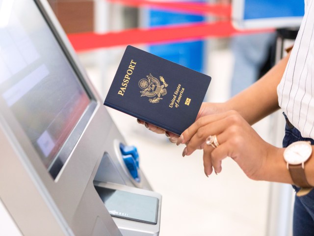 Close-up image of person holding U.S. passport at airport kiosk machine