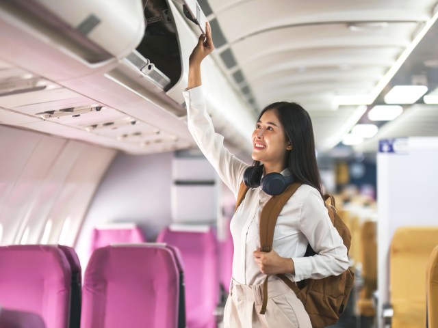 Passenger on airplane closing overhead bin