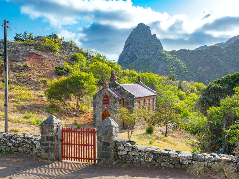 Small stone church on St. Helena Island surrounded by rocky mountain landscape 