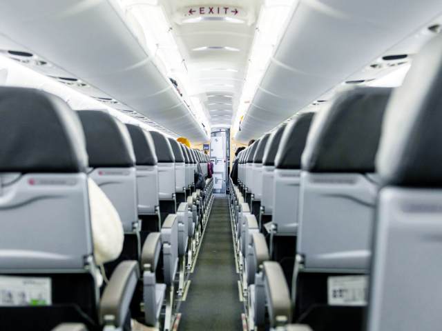 View toward front of narrow-body aircraft cabin from aisle