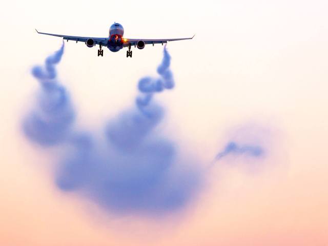 Plane on approach with jet trail behind