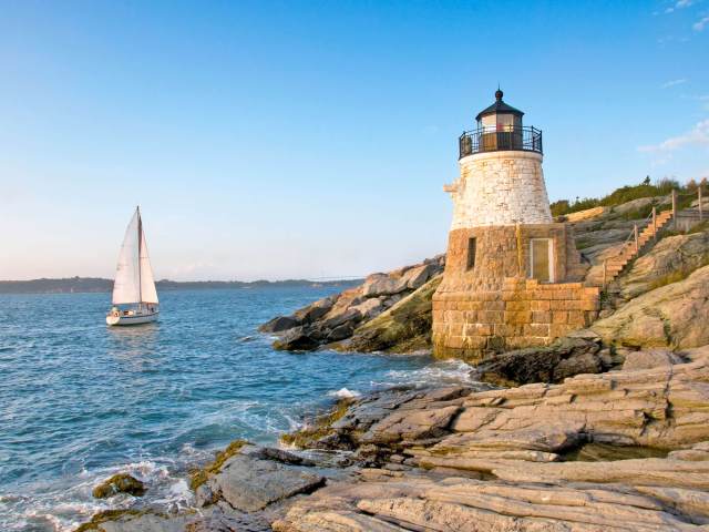 Sailboat and lighthouse along rocky coast of Rhode Island
