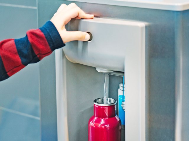Person using water fountain to fill refillable water bottle