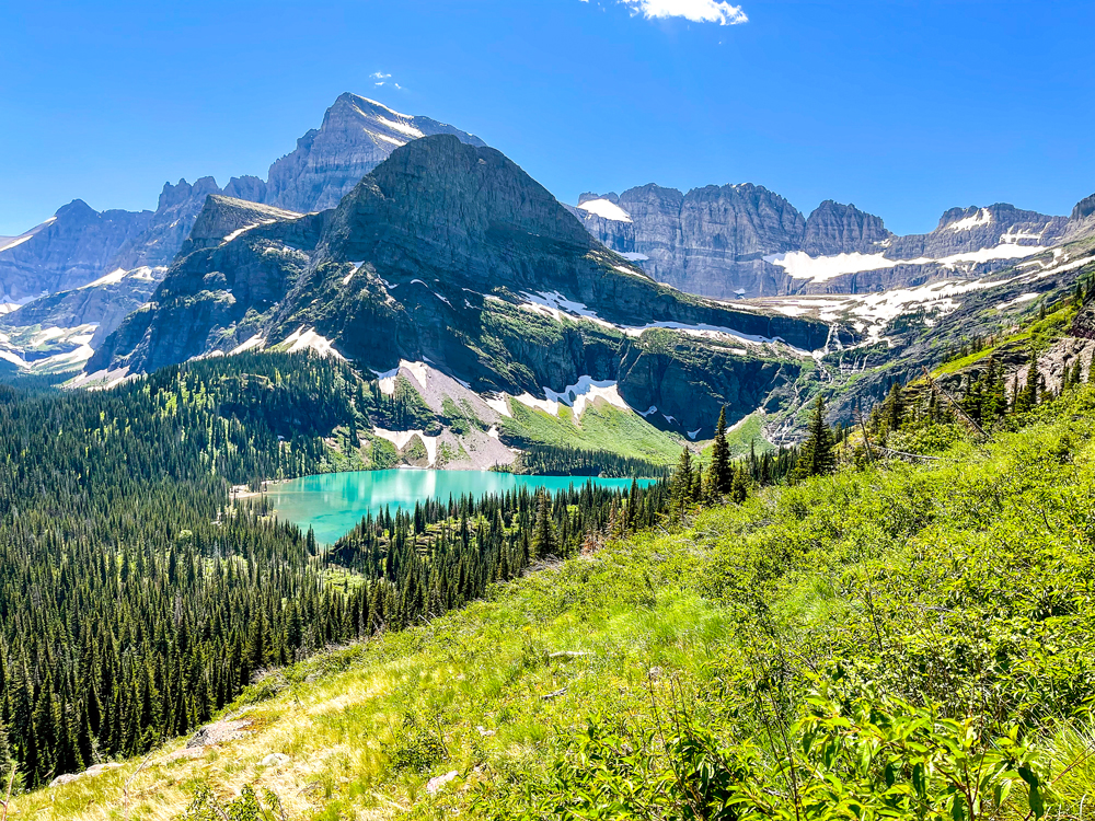 View of glacial lake, forest, and snow-covered mountains in Montana's Glacier National Park