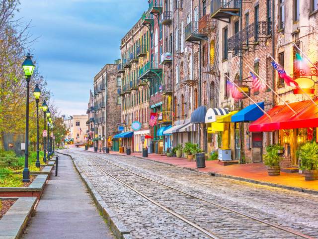 Street lamps, cobblestones, and brick storefronts and residential buildings along River Street in Savannah, Georgia