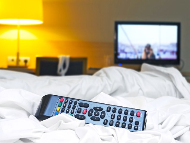 Close-up image of TV remote on hotel bed