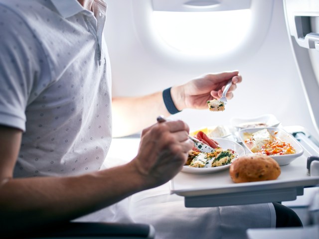 Passenger consuming in-flight meal on tray table