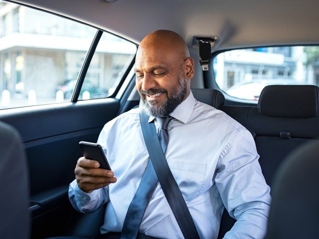 Rider in back of taxi looking at his phone