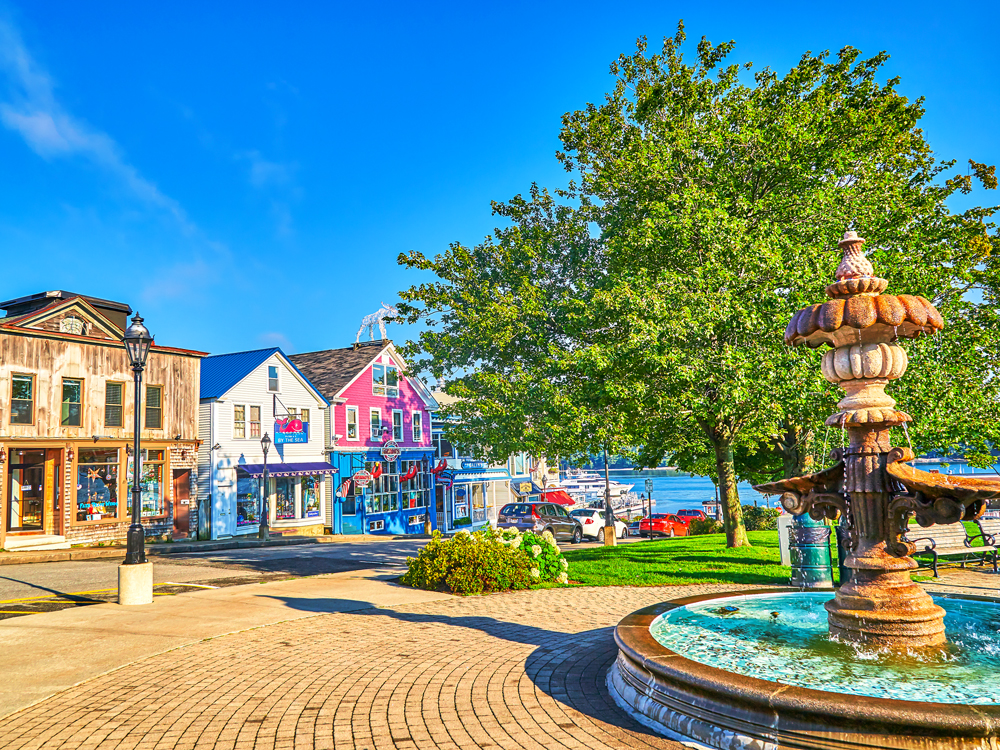 Fountain in park next to colorful buildings of Bar Harbor, Maine
