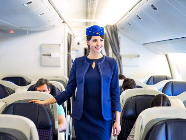 Flight attendant walking down airplane aisle