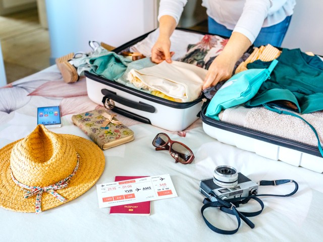 Person laying items out on bed to pack in suitcase