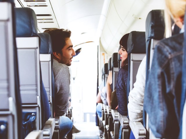 Couple talking to one another across airplane aisle