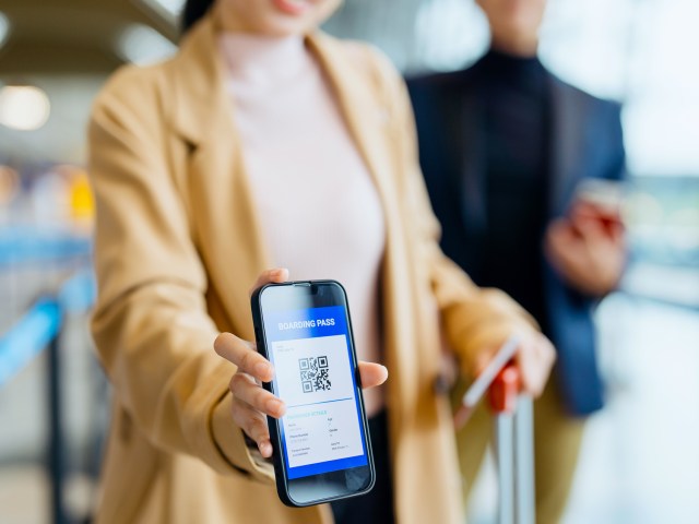 Traveler at airport showing boarding pass on smartphone