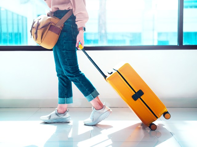 Traveler rolling yellow suitcase through airport