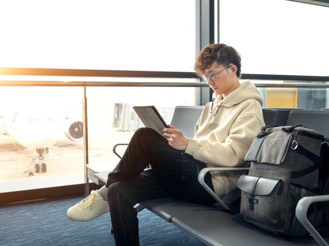 Traveler sitting at airport gate looking at tablet