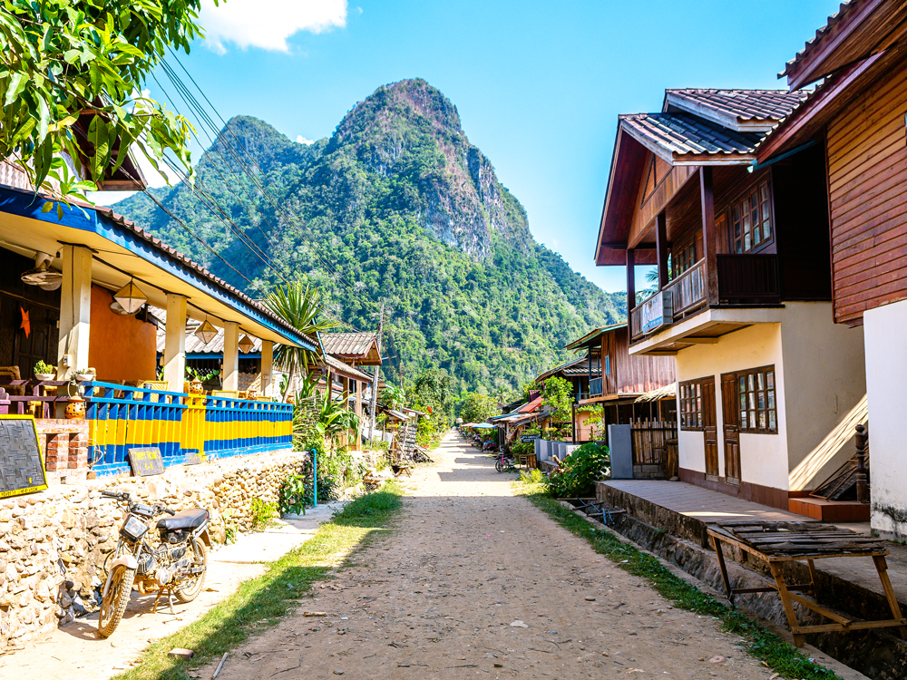 Street lined with homes leading toward mountains in Laos