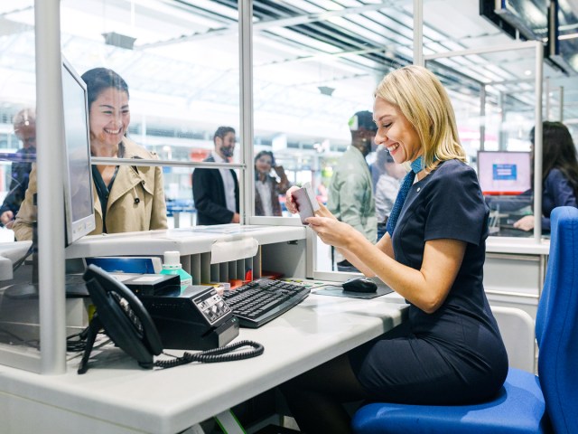 Airport check-in agent reviewing traveler's passport