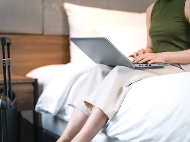 Person using laptop on hotel bed