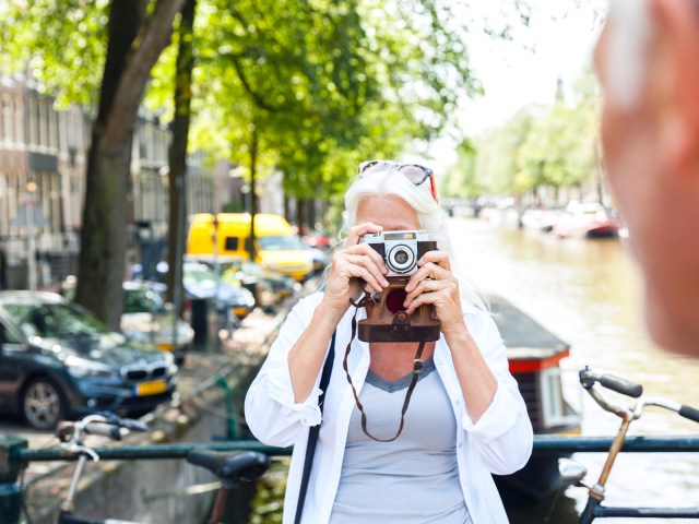Traveler taking photo of companion next to canal