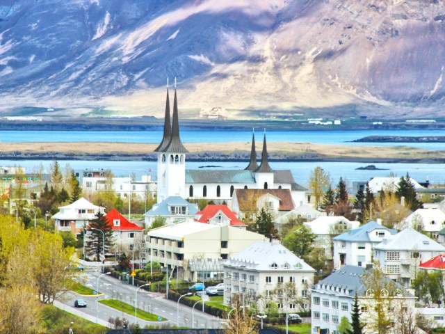 Church towers and other buildings with water and mountains in background in Reykjavik, Iceland