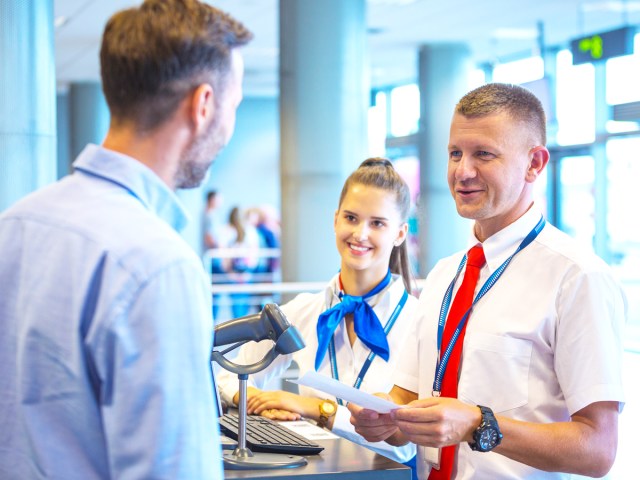 Gate agent handing passenger ticket at airport 