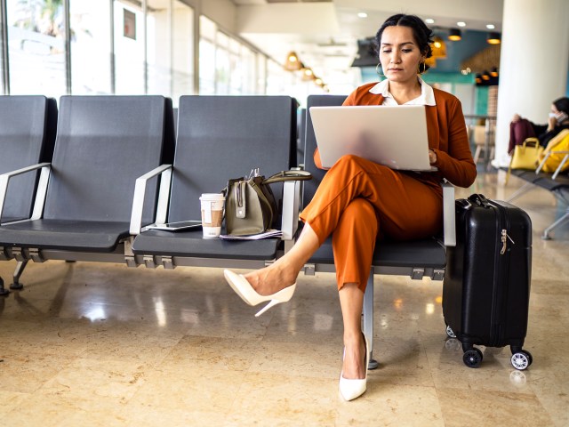 Traveler sitting in airport working on laptop