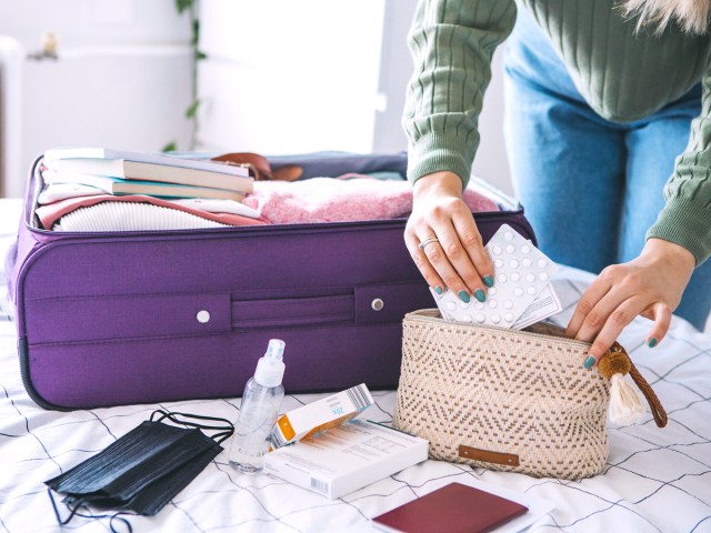 Traveler packing medicine in suitcase