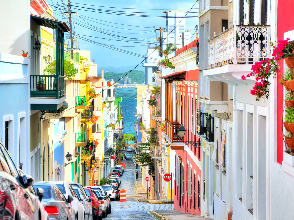 Narrow, hilly street looking toward sea and flanked with colorful homes in Old San Juan, Puerto Rico