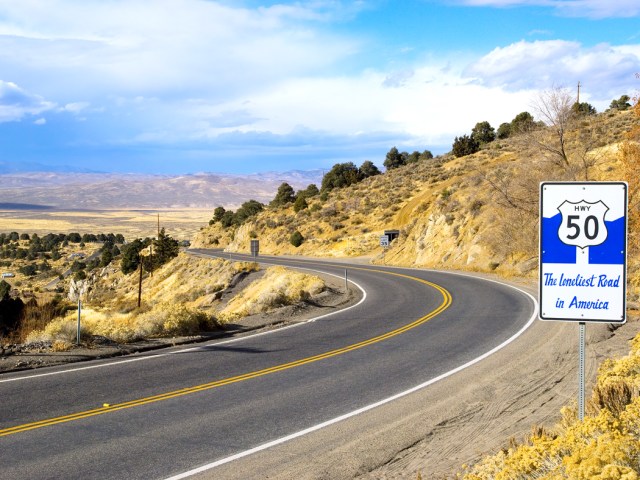 Curving section of U.S. Route 50 in Nevada with sign dubbing in the "Loneliest Road in America"