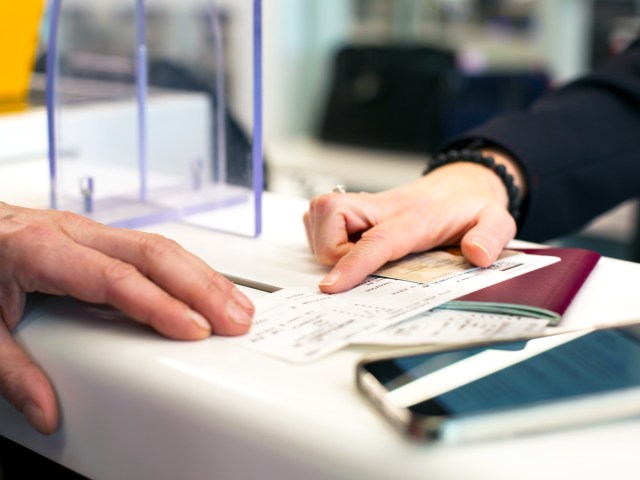 Close-up view of airport agent and traveler reviewing ticket at check-in counter