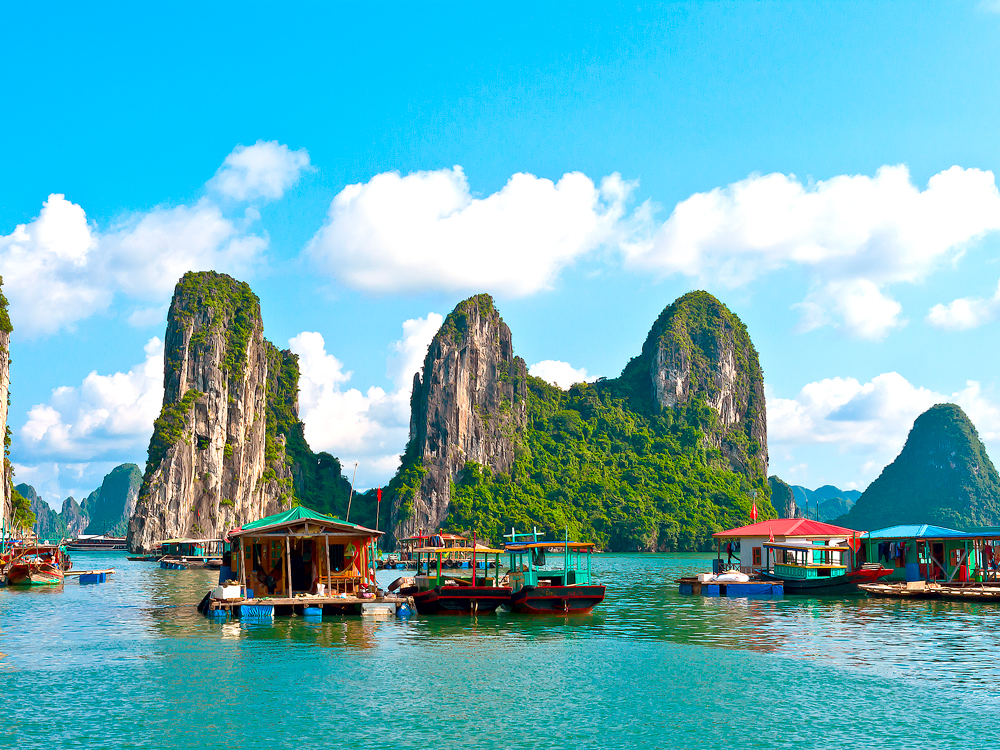 Towering limestone rock formations and traditional boats and floating docks in Ha Long Bay, Vietnam