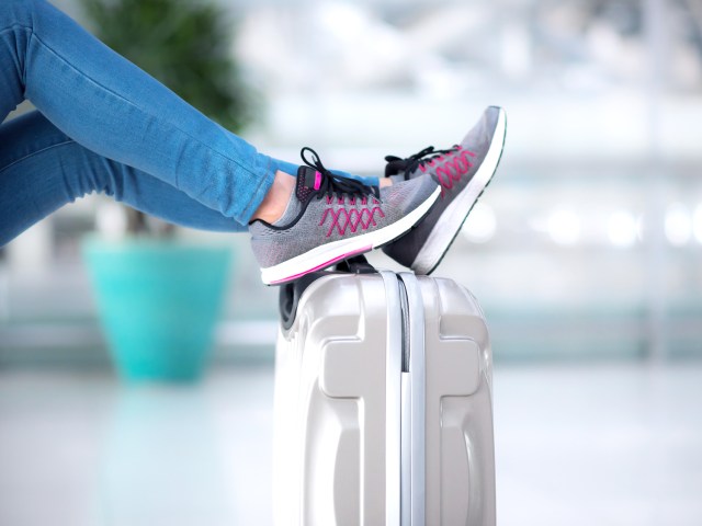 Person resting sneakers on suitcase