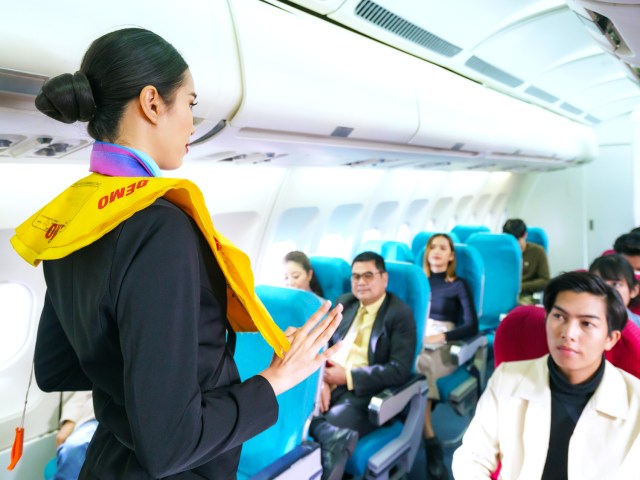 Flight attendant performing safety demonstration on airplane