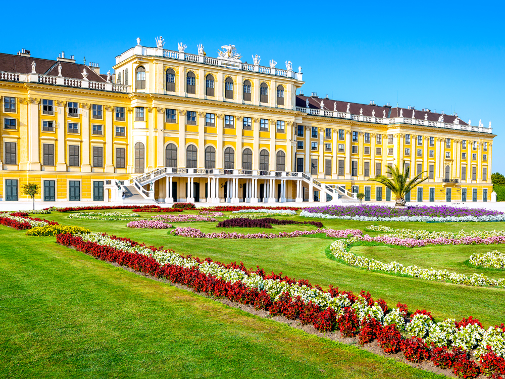 Grand yellow exterior and manicured gardens of Schönbrunn Palace in Austria