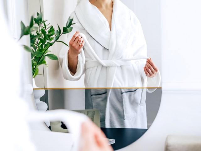 Person wearing bathrobe in front of mirror