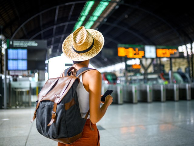 Traveler at train station wearing hat and backpack