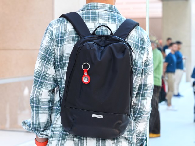 Person wearing Apple AirTag on keychain attached to backpack