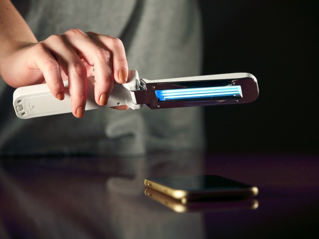 Person using UV light sanitizer on cellphone