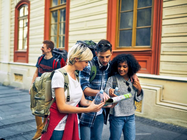 Group of travelers in city huddled around map