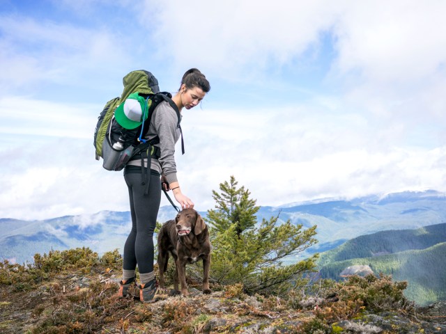 Hiker and her dog on mountaintop