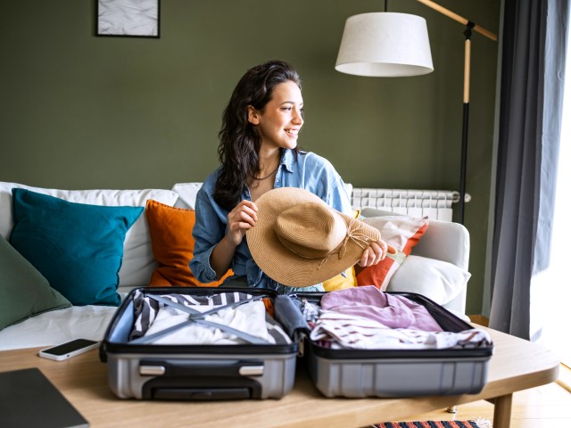 Traveler packing hat into suitcase
