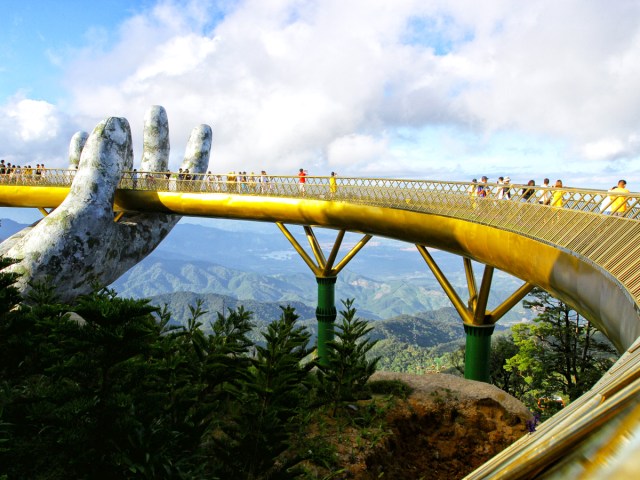 Tourists walking on Golden Bridge, held up by a statue of a human hand, in Vietnam