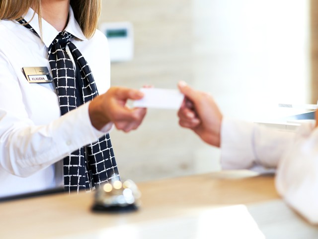 Hotel receptionist handing guest key card