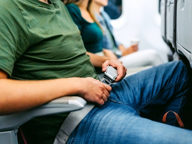 Airplane passenger fastening seatbelt