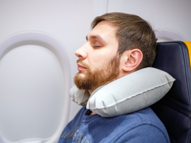 Airplane passenger sleeping with inflatable neck pillow