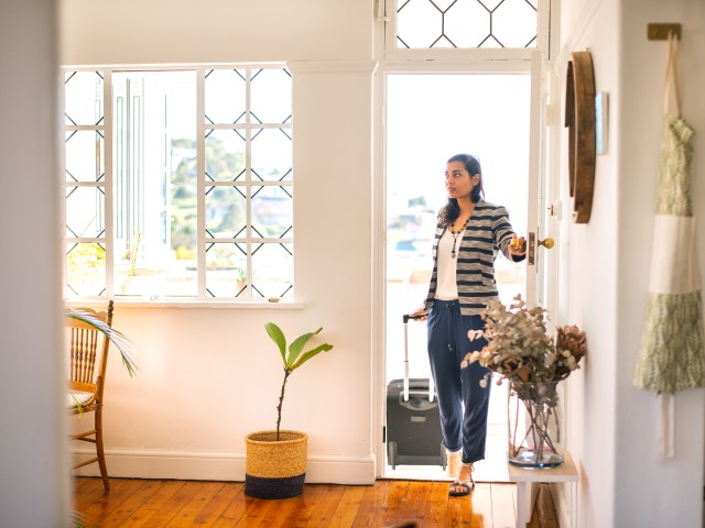 Traveler entering vacation rental home with suitcase