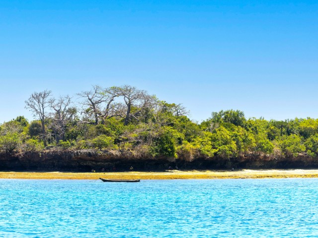 Small boat off beach and aquamarine waters of Kisite-Mpunguti Marine Park and Reserve in Kenya